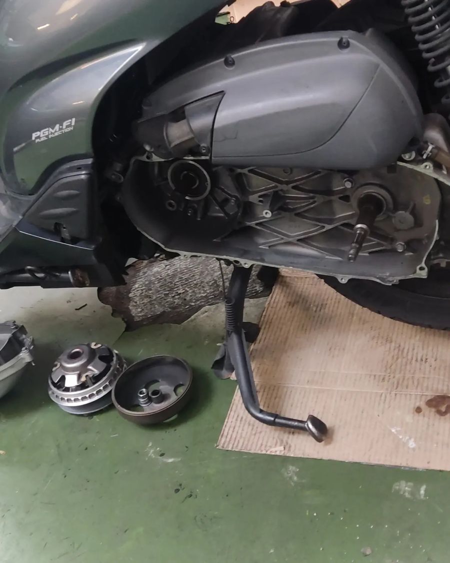 Honda SH300i con el cárter de la transmisión abierto sobre el suelo verde
