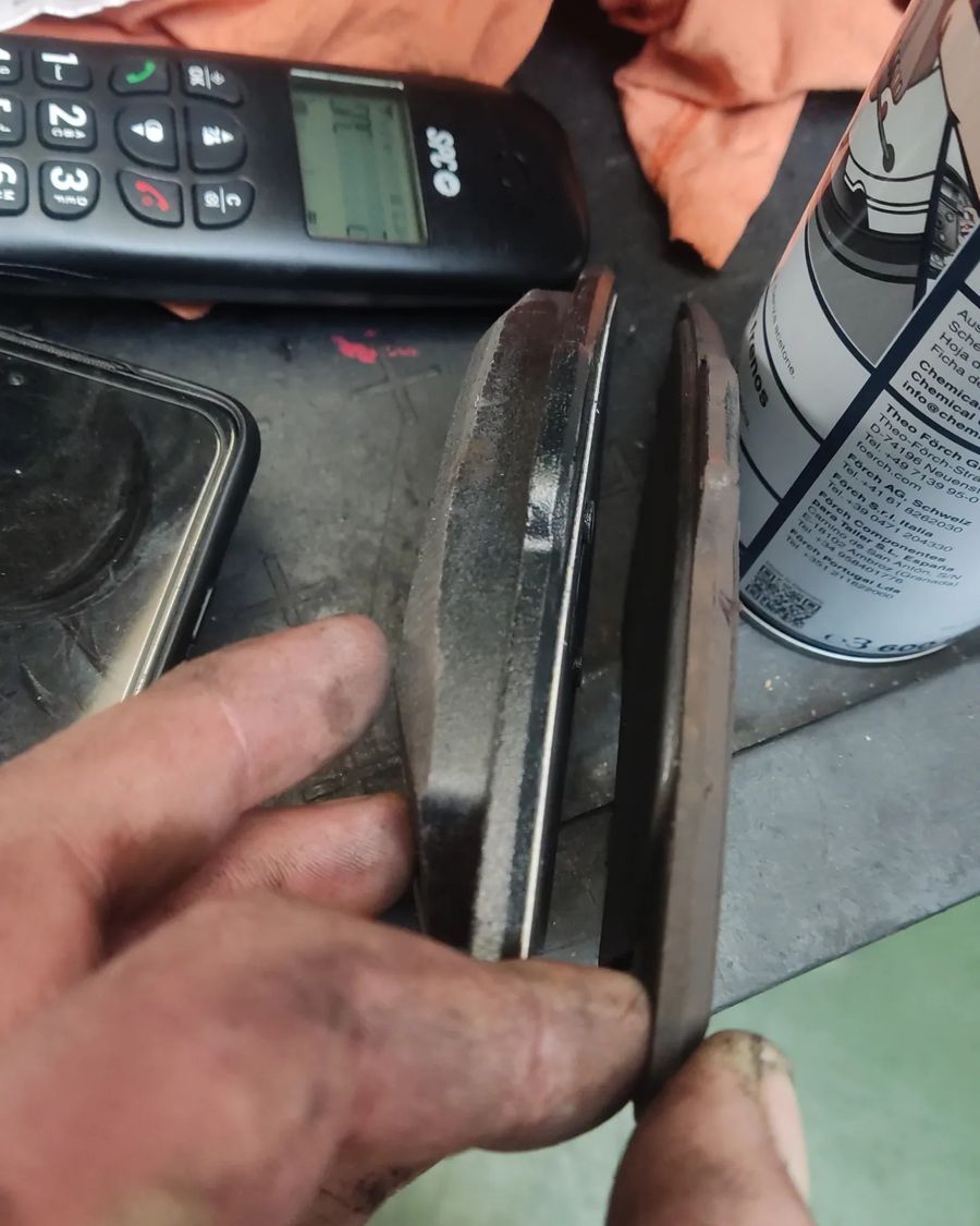 Mano enseñando el grosor de una pastilla de freno gastada